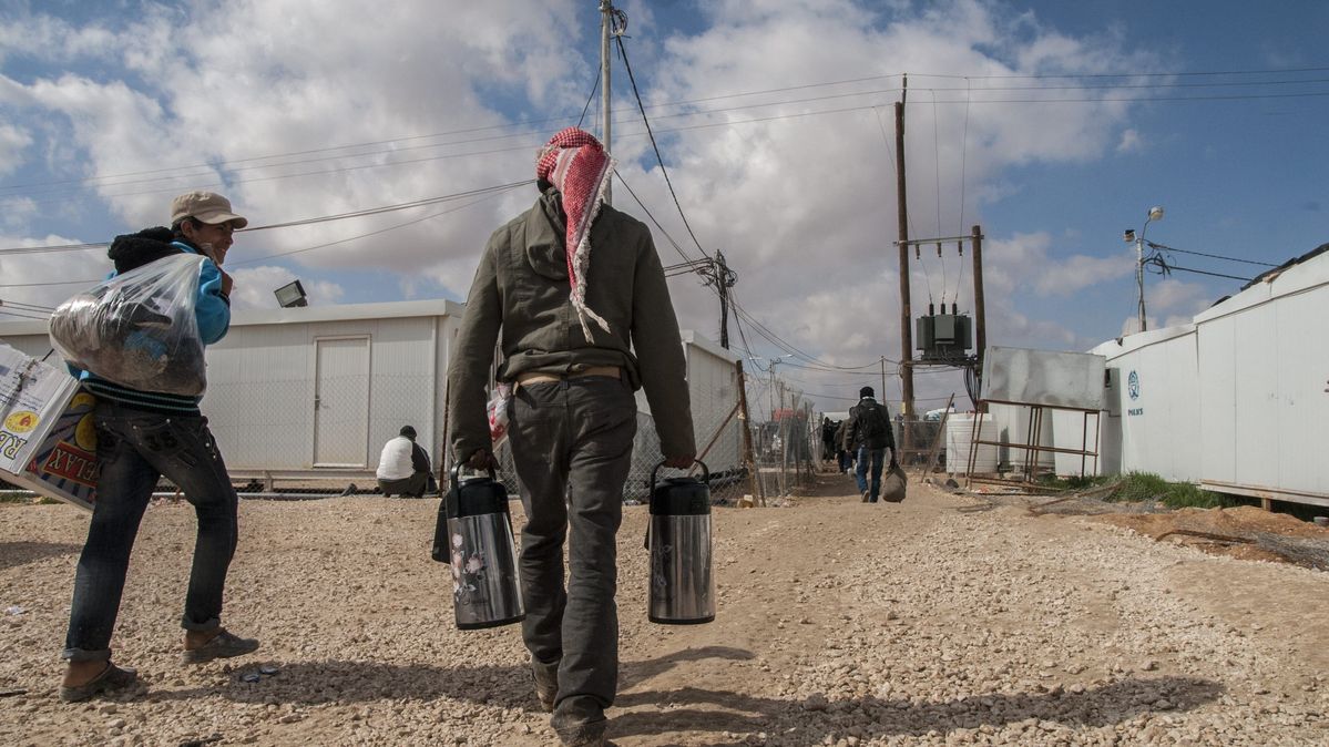 Syrische Flüchtlinge im Flüchtlingslager Zaatari an der jordanisch-syrischen Grenze Zwei Männer laufen in Richtung eines Lagers aus Wohncontainern.