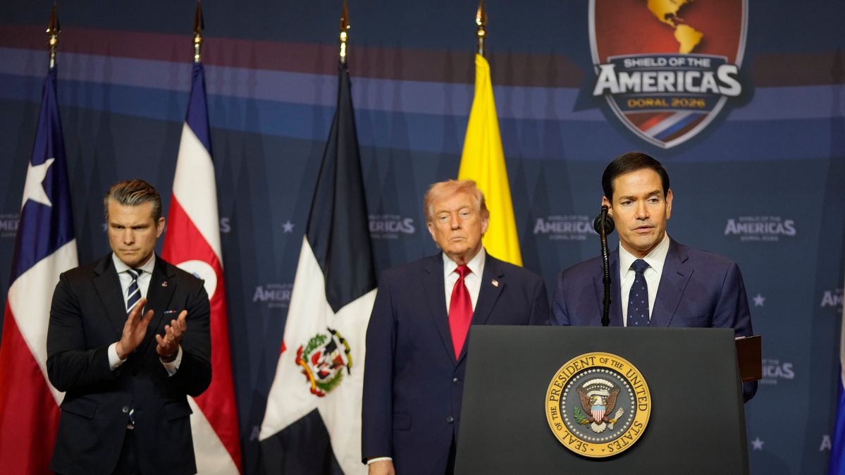 US-Verteidigungsminister Hegseth, US-Präsident Trump und US-Außenminister Rubio während des „Shield of the Americas“ Gipfels in Florida am 7. März 2026. US-Verteidigungsminister Hegseth, US-Präsident Trump und US-Außenminister Rubio vor verschiedenen Nationalflaggen Mittel- und Südamerikas