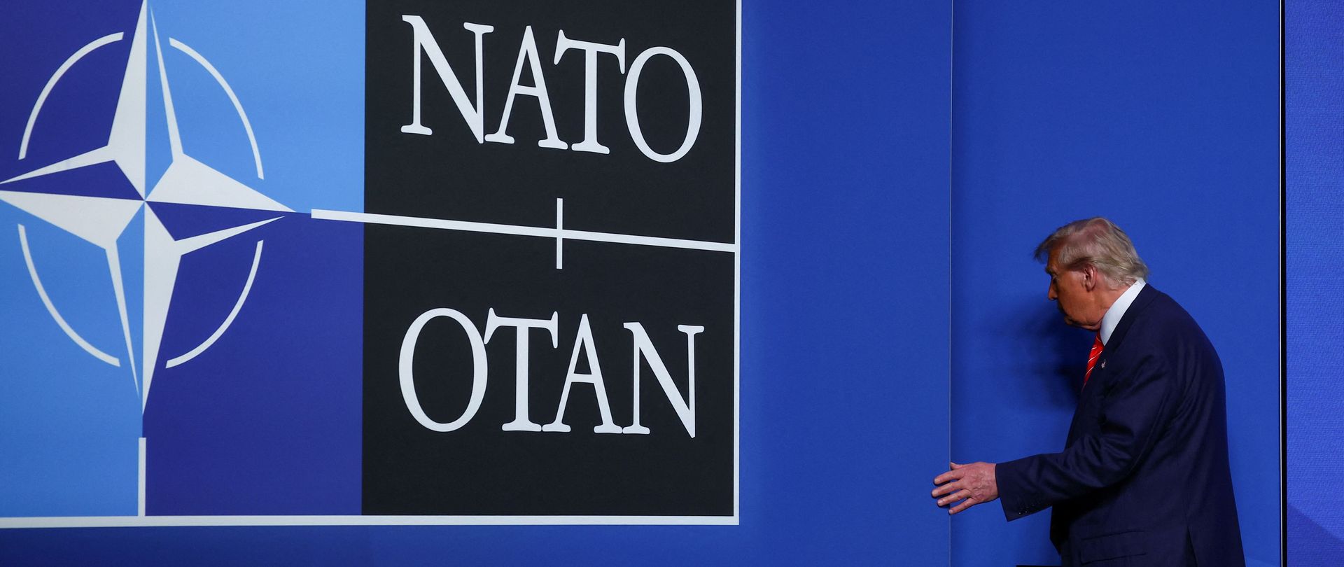 US-Präsident Donald Trump verlässt die Pressekonferenz beim Nato-Gipfel in Den Haag. Donald Trump neben einer blauen Wand mit NATO-Logo