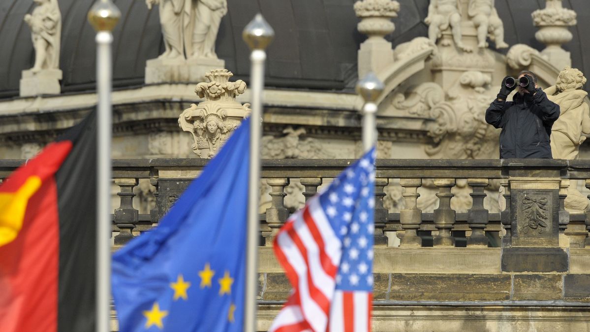 Ein Sicherheitsbeamter mit Fernglas während eines Staatsbesuchs Ein Beamter mit Fernglas hinter drei Flaggen