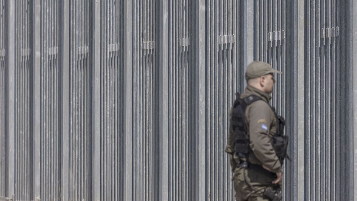 Ein griechischer Grenzpolizist patrouilliert an der Grenze zur Türkei. Ein Polizist in Uniform vor einem hohen Grenzzaun
