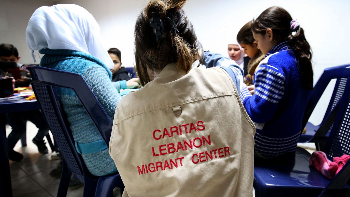 Geflüchtete, syrische Kinder nehmen an einem Kunsttherapie-Kurs in einem Caritas-Zentrum im Libanon teil. Eine Person, die eine Jacke mit der Aufschrift »Caritas Lebanon Migrant Center« trägt, leitet eine Gruppe von Kindern an.