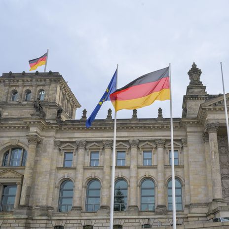 Berliner Reichstagsgebäude mit Deutschland- und Europaflagge